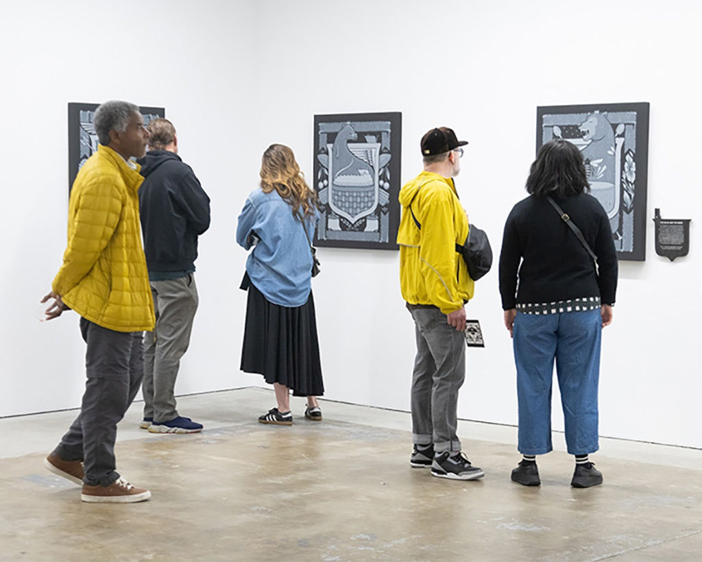 image of a group of people looking at paintings by the artist Jeremy Fish at the opening reception of his exhibition 