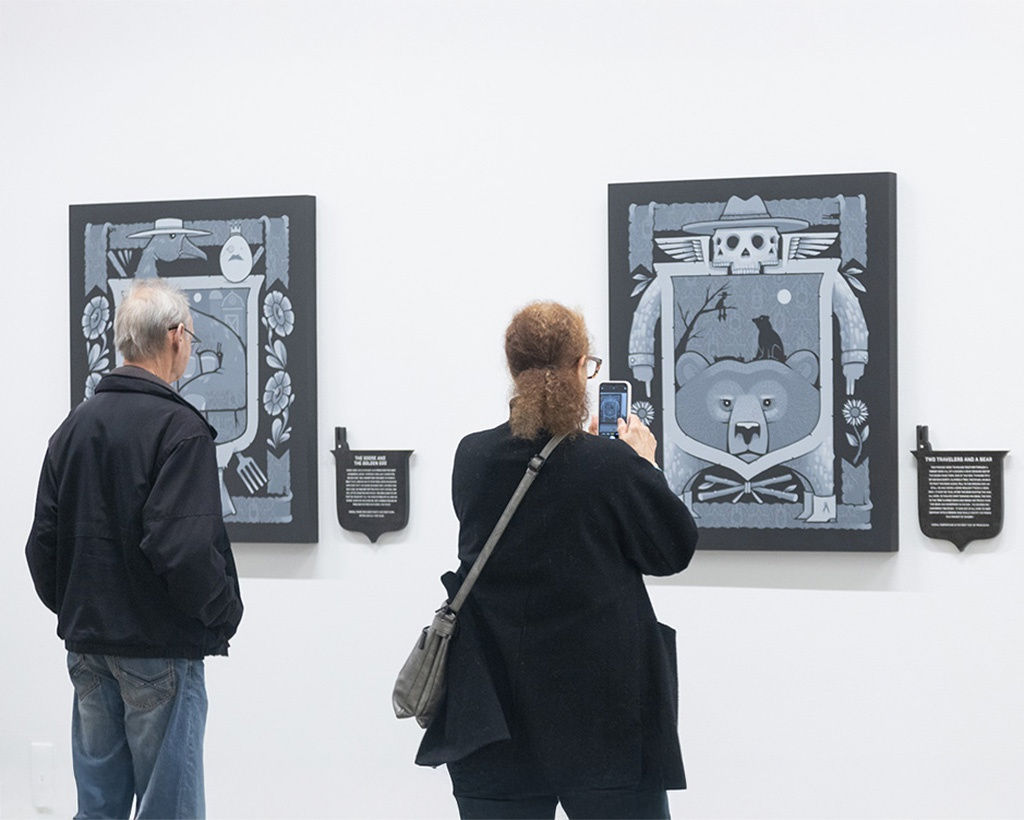 image of two visitors taking a photo of artist Jeremy Fish's opening reception at Harman Projects San Francisco