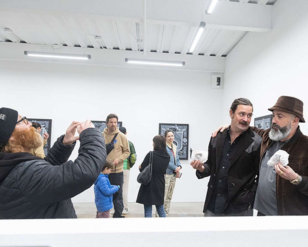 image of artist Jeremy Fish posing for a photo with a friend at the opening reception for the exhibition 