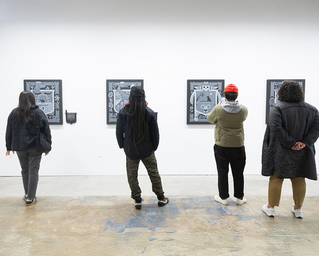 Image of four visitors standing in front of four paintings by artist Jeremy Fish at the opening reception for his exhibition 