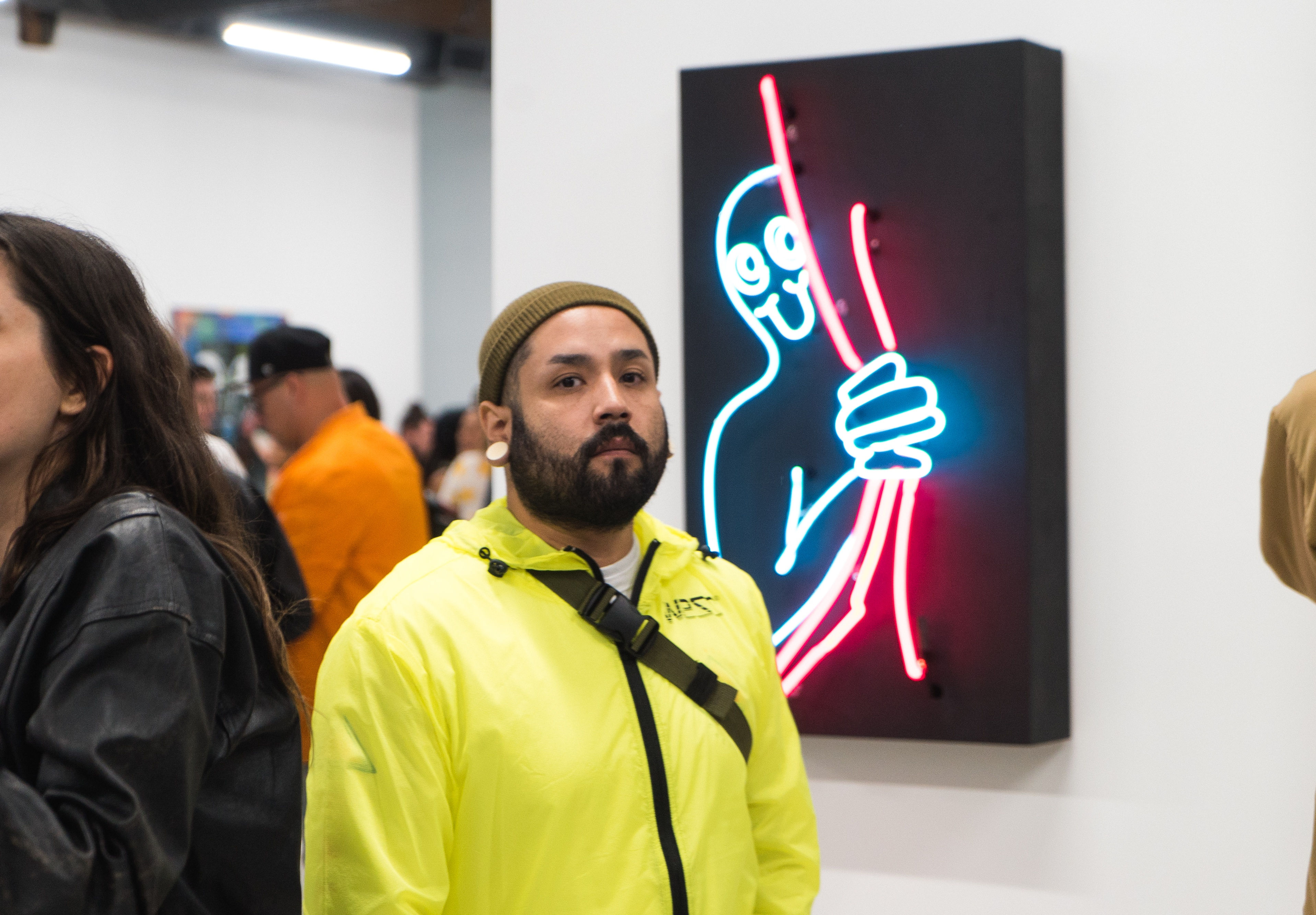 photo of a man standing in front of a neon art piece