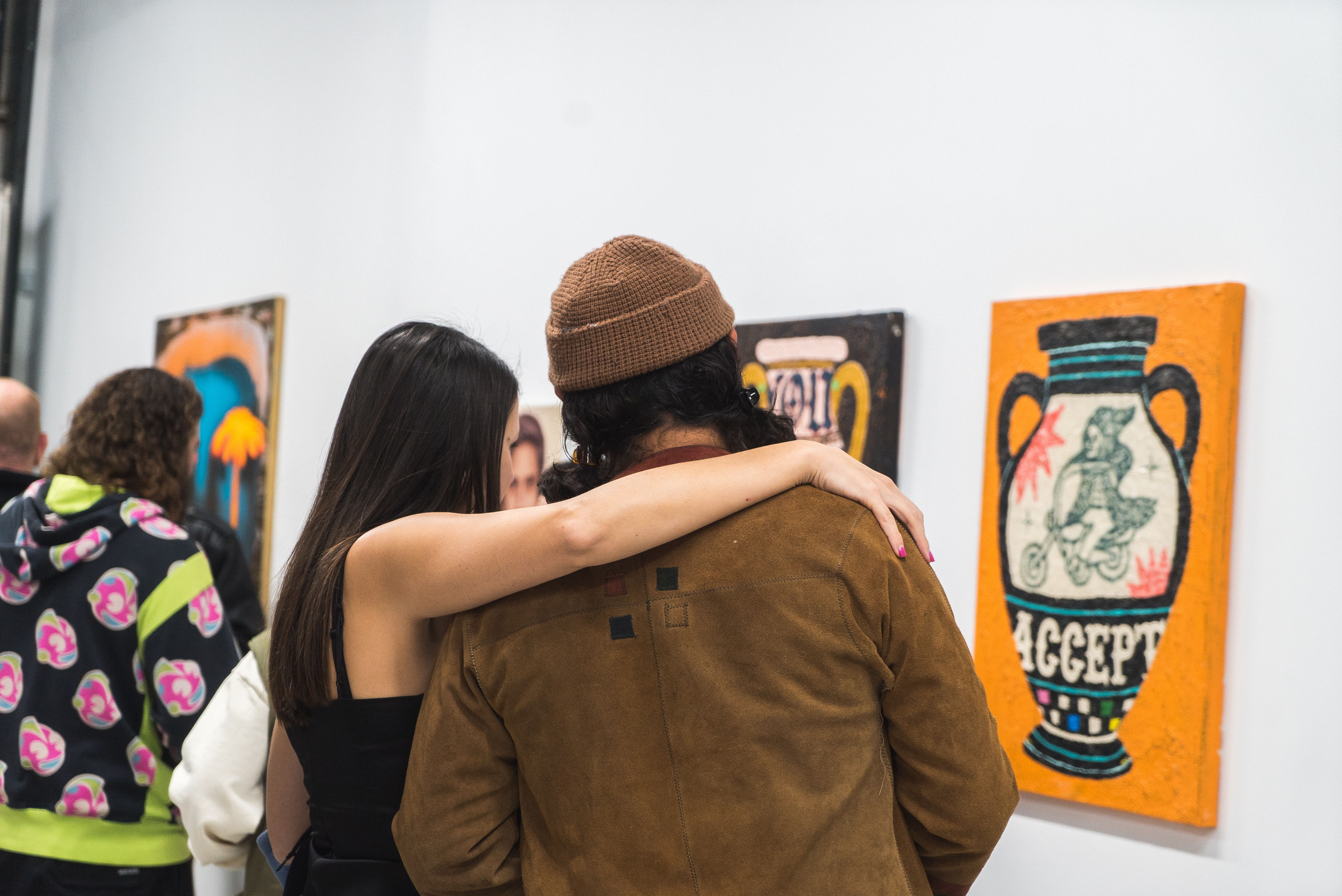 photo of a couple standing in front of Julien Jaca's orange vessel painting