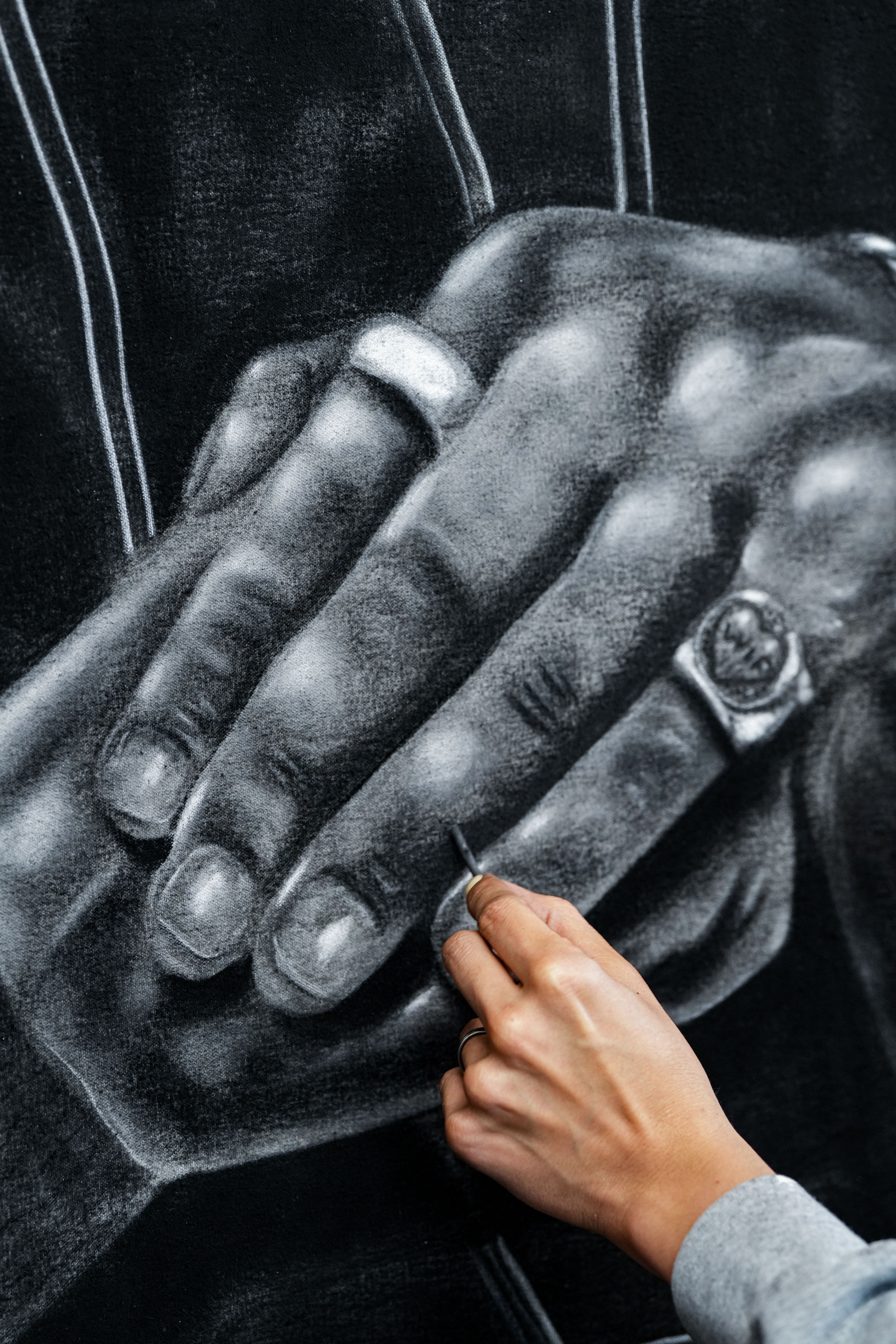 Photo of the artist using charcoal to create a drawing on hands