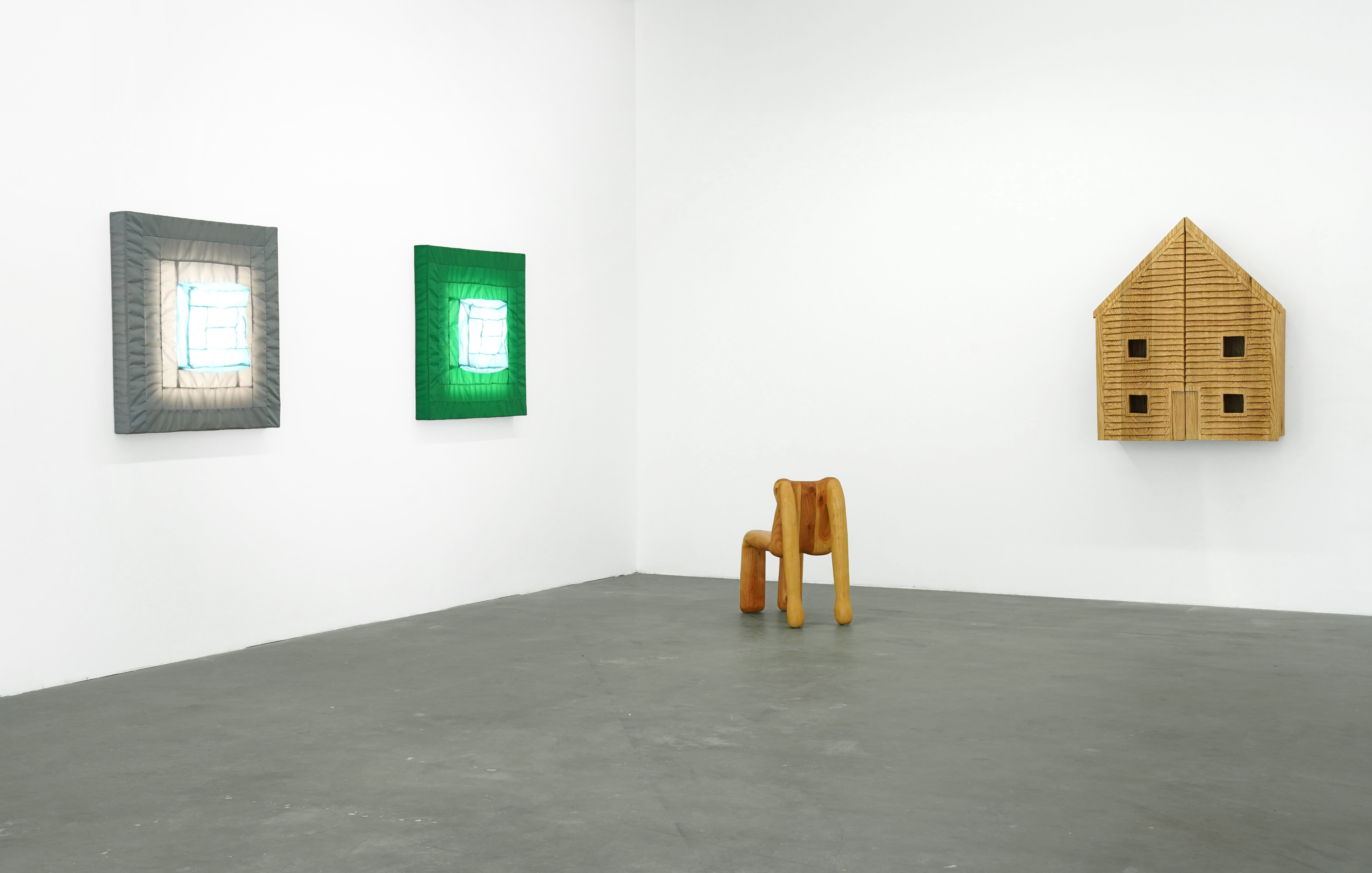 photo of an art installation in the gallery featuring a wooden chair shaped like a human and 2 wall mounted lights by Ryan Belli
