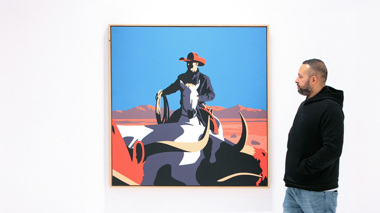 Jeremy Booth painting cattle run with cowboy hearding a cow with a man standing next to it for scale
