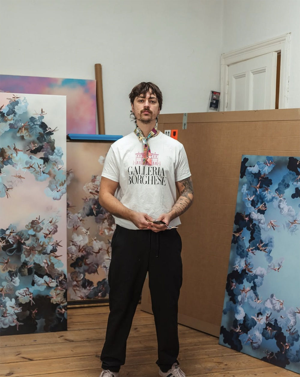 Artist Paul Kuntze standing in his studio with artworks around him 