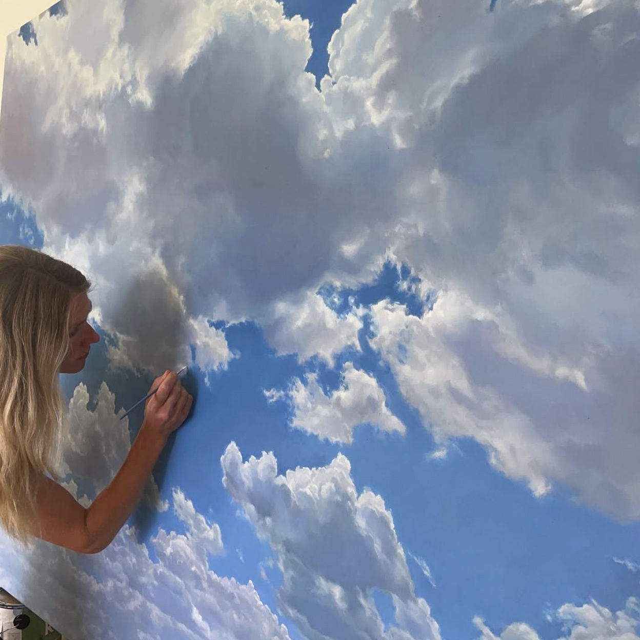 Rachel English in the studio painting a cloudscape painting 