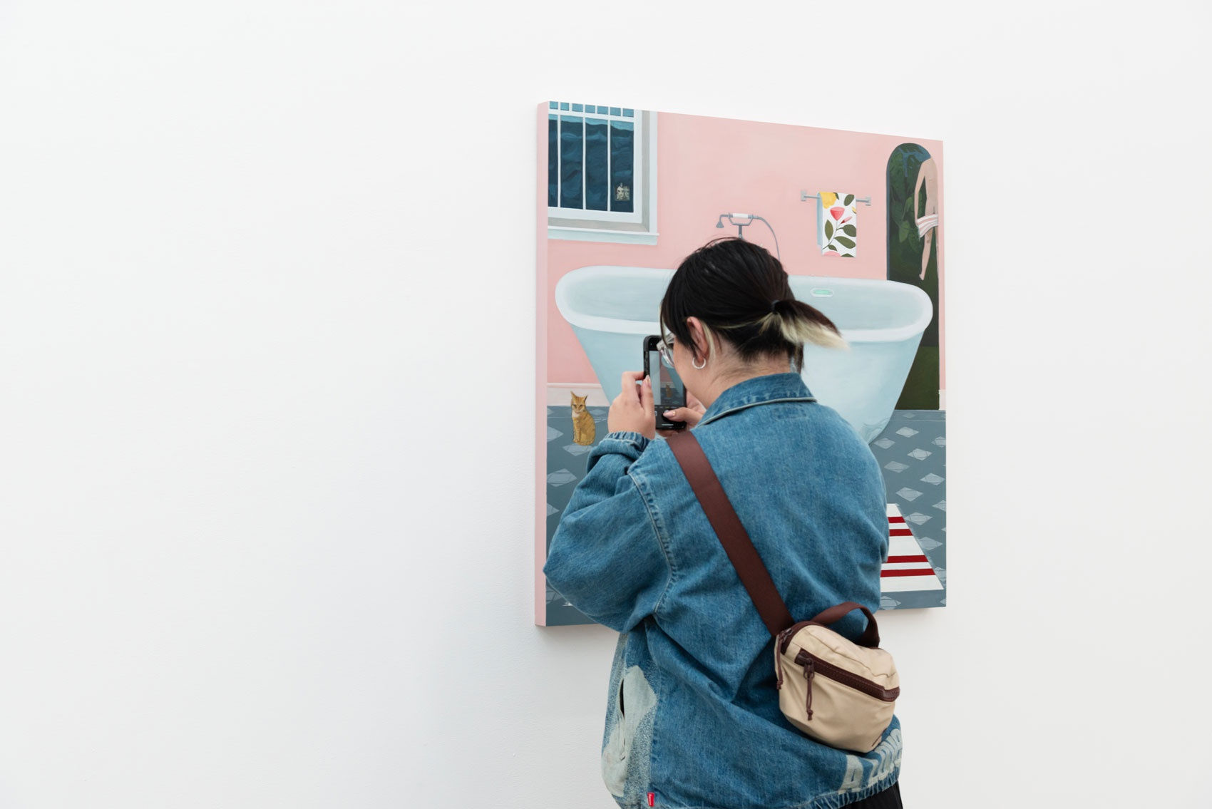 Two people look at Angela Burson's painting in an art gallery with white walls. 