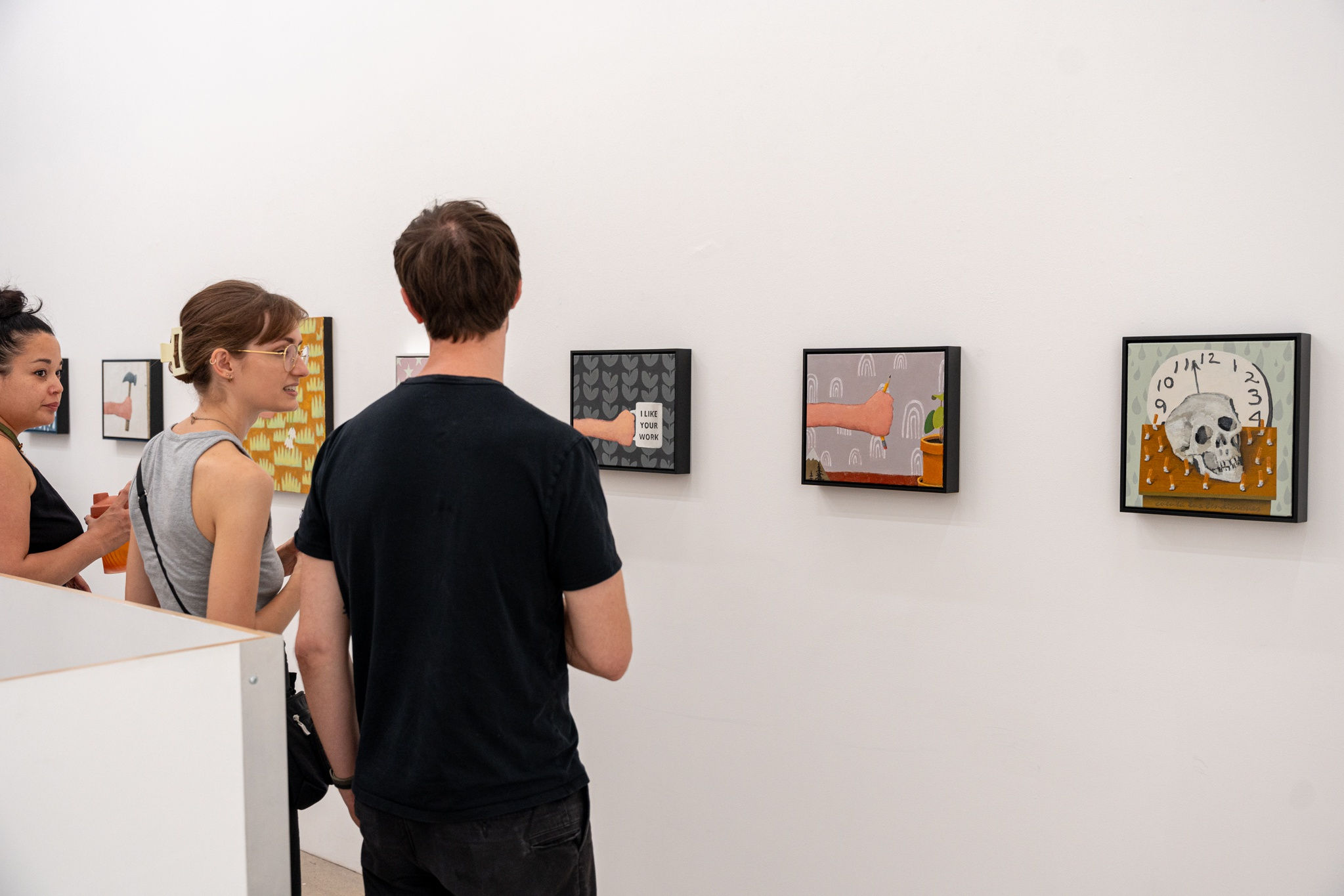 photo of three people looking at Gabe Langholtz's artwork at the opening reception