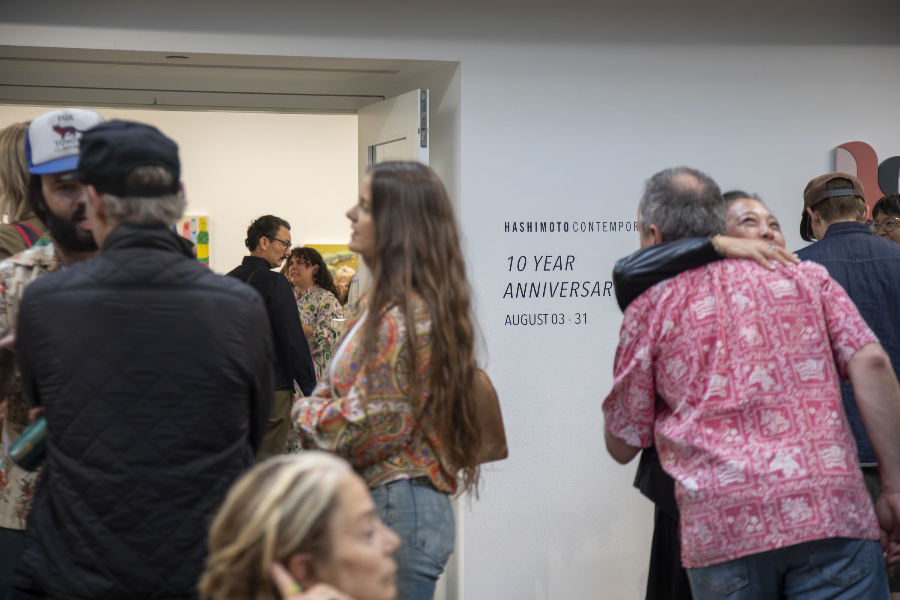 People hug and mingle in front of the doors to the gallery