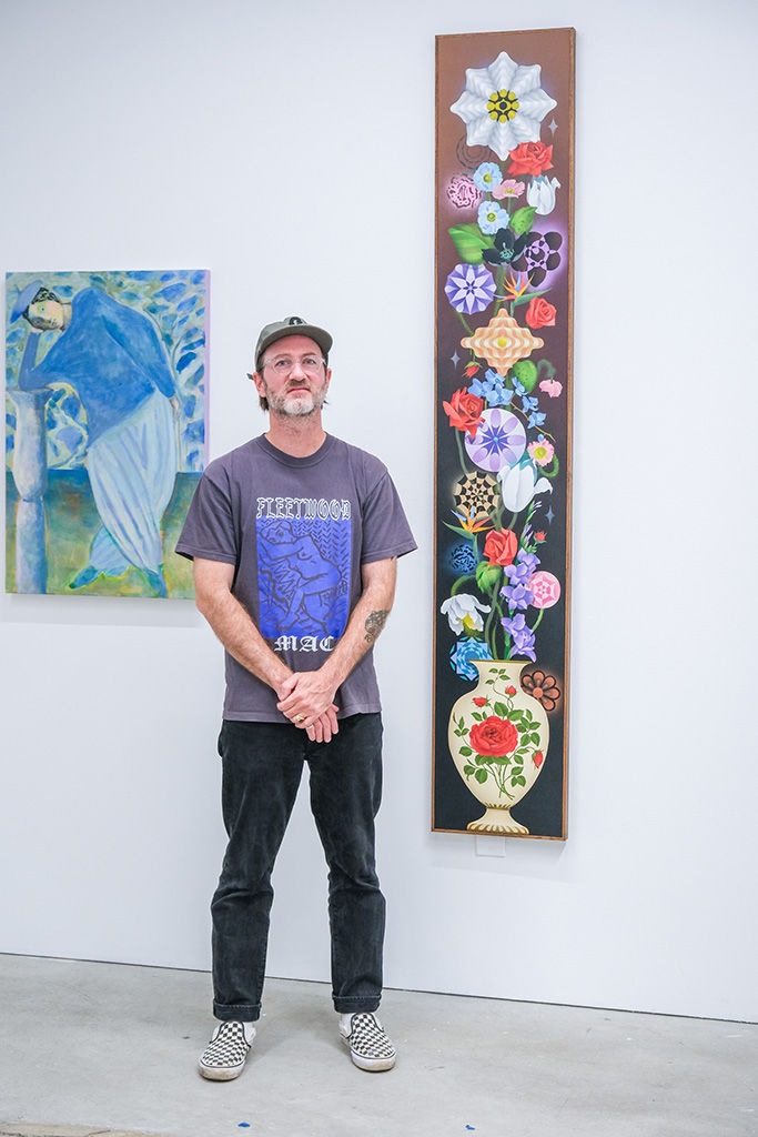 Photo of artist Casey Gray next to his work at the opening reception of 