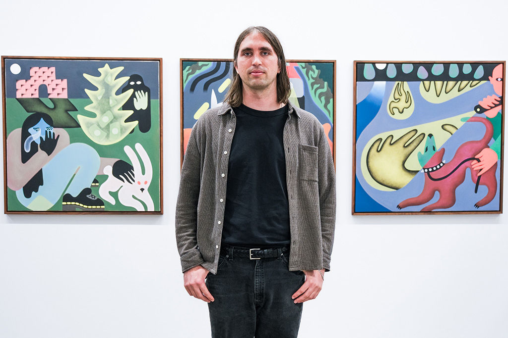 Photo of artist Austin Elfio Montanari next to his work at the opening reception of 