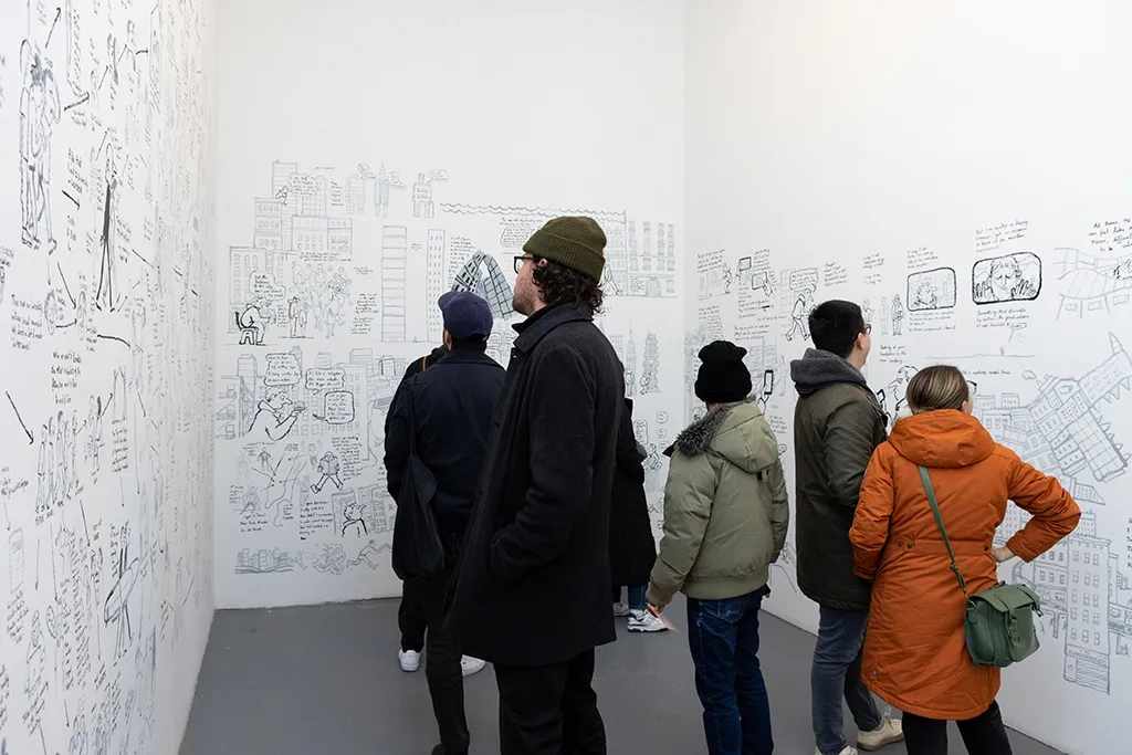 Visitors look at Jean Jullien's painting on a white wall. 