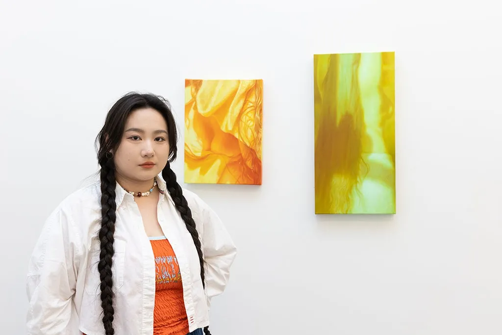 Artist Jesse Zuo standing with her art