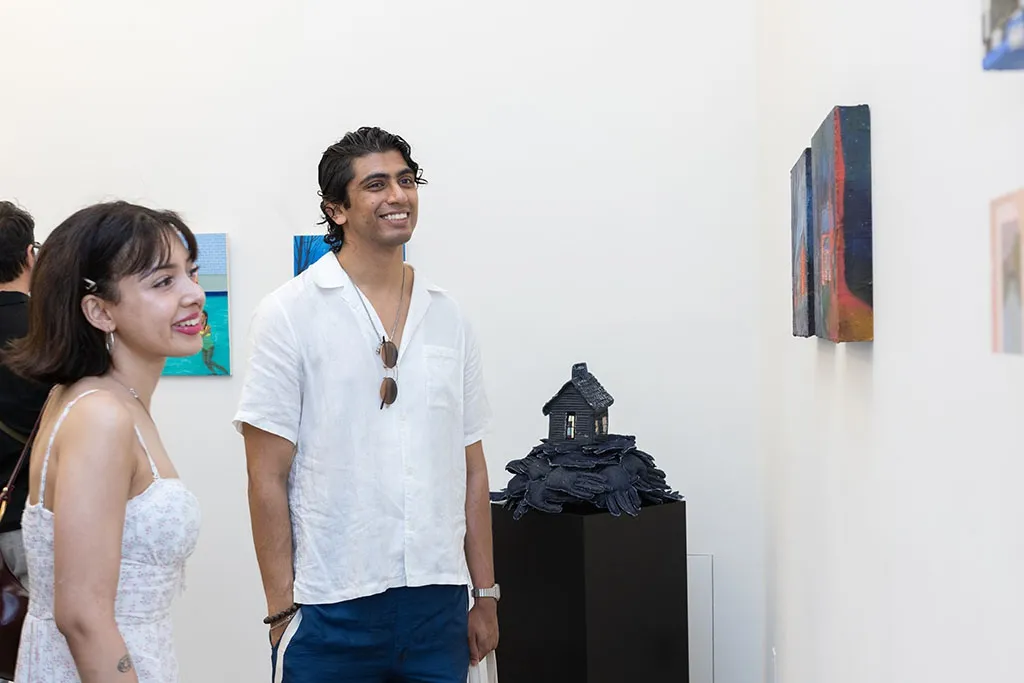 People standing looking at art at the opening of Left Unsaid