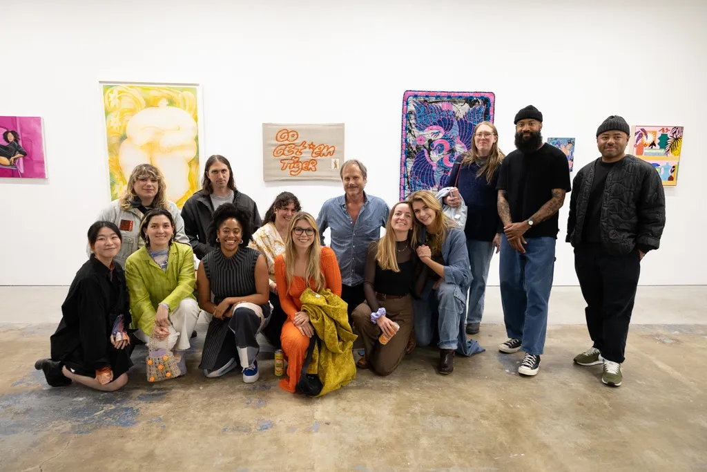 A group of artists pose for a photo in a white wall contemporary art gallery. 