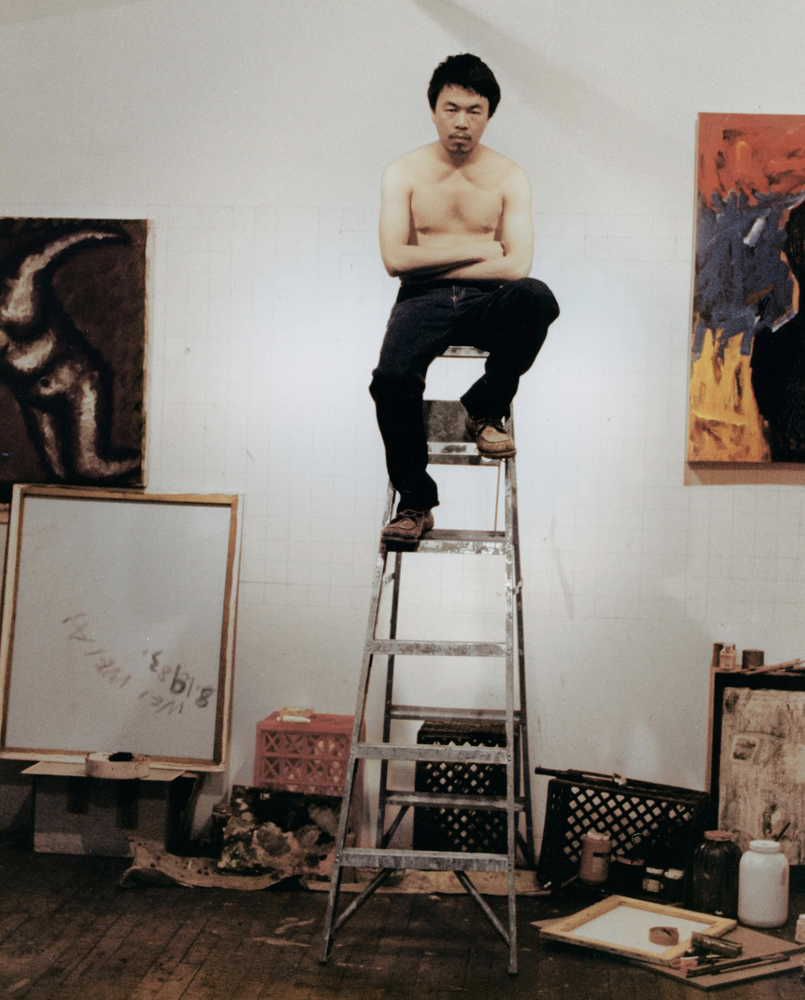 a young man sits on top of a ladder in a studio