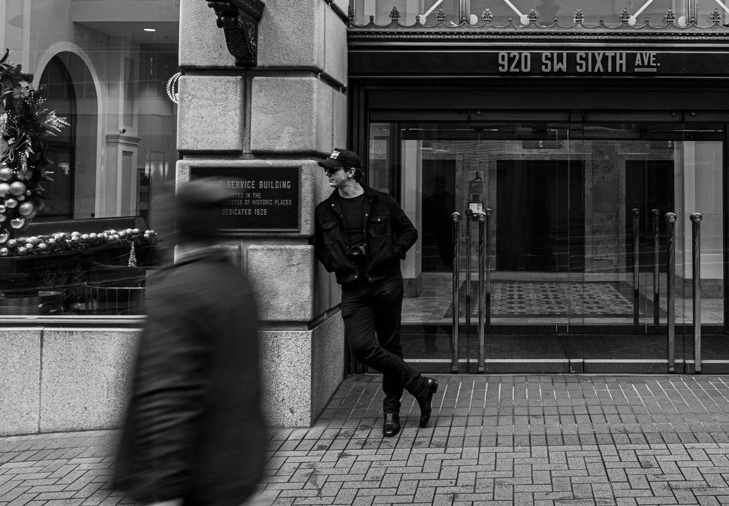 Artist Garrett Gassman standing in a Portland, Oregon street during the 2020 lockdown, captured in a high-contrast black and white style to match the Surreal Memory photography series.
