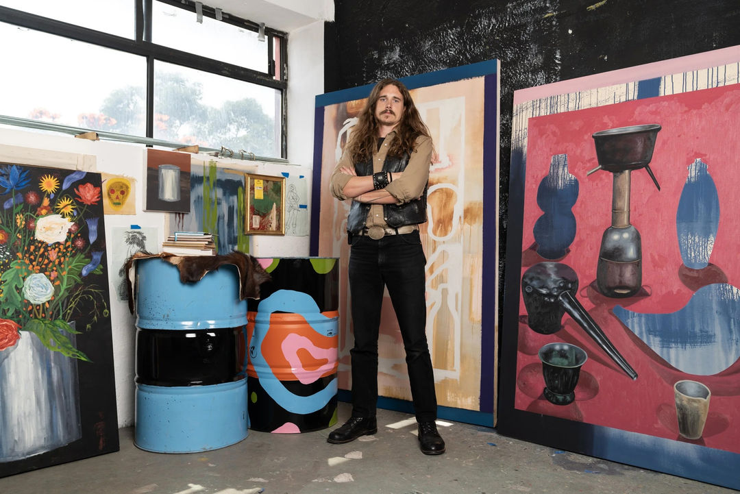 photo of the artist standing in front of his paintings