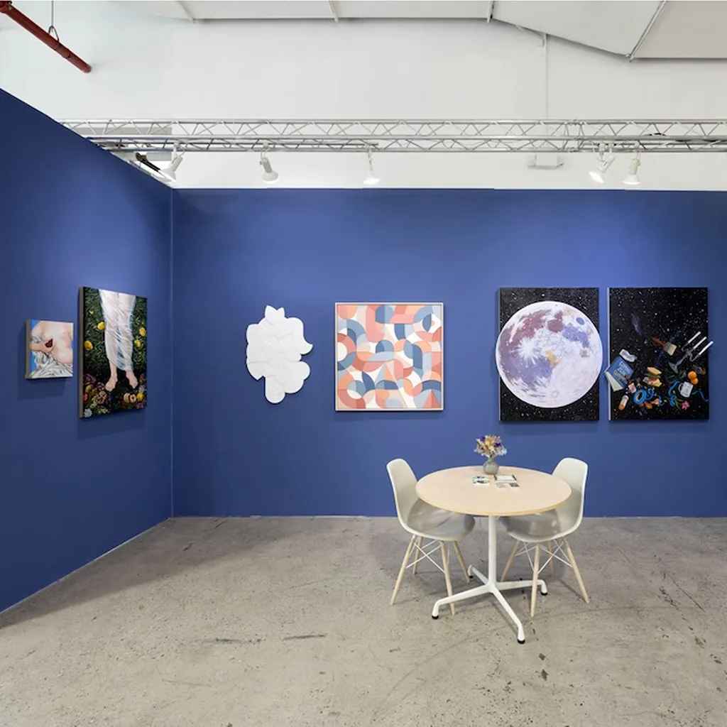 blue booth with various artworks hanging on walls. round table to the right