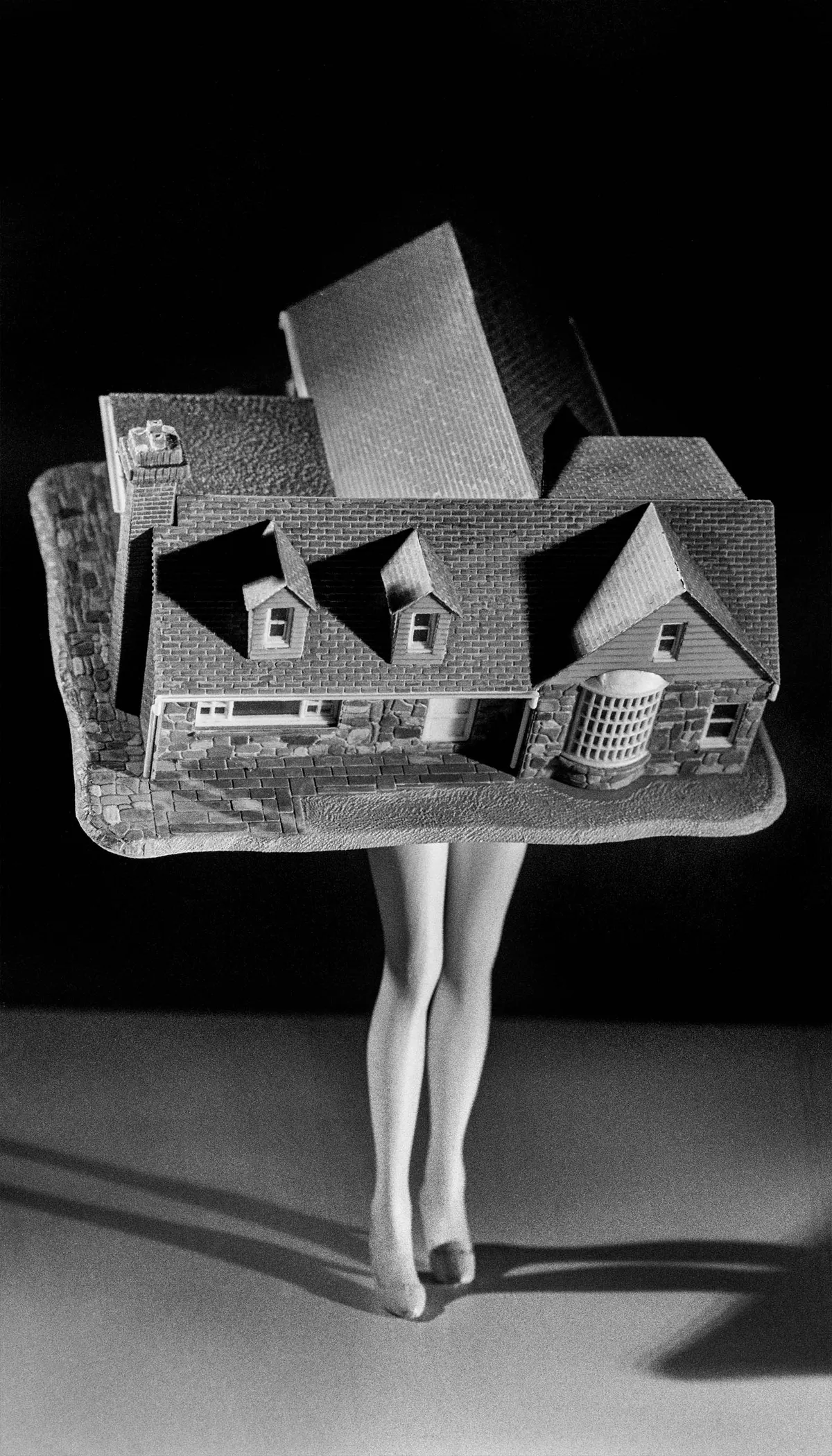 Laurie Simmons black and white photograph of a miniature house with female legs in heels