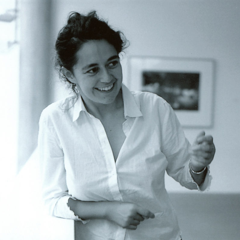 Black and white image of person in white dress shirt smiling away from the camera.