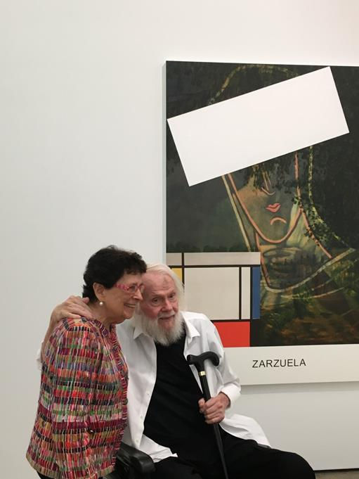 Marian Goodman and John Baldessari in front of a Baldessari artwork on the wall. 
