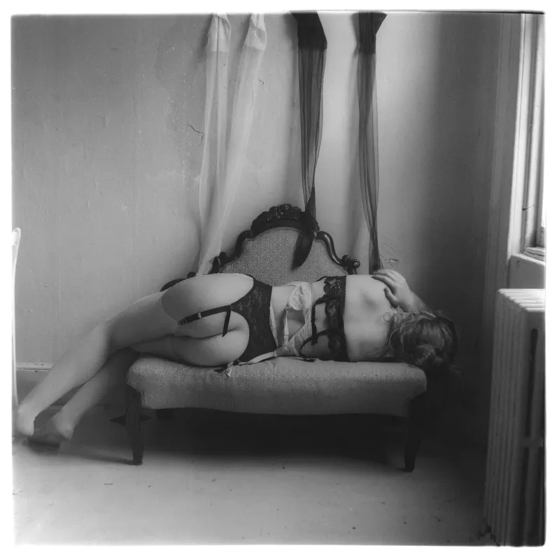 A woman lying down on a couch, with her back facing the viewer.