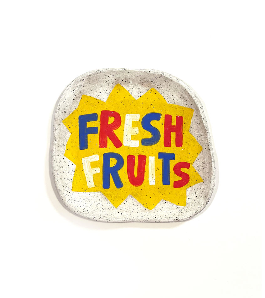 Jackie Brown's sculpture with of a plate with the words fresh fruit painted on in primary colors