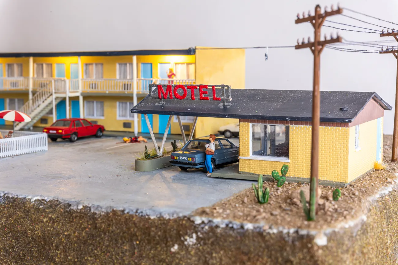 miniature diorama by Abigail Goldman of a woman bleeding on the ground in the parking lot of a motel