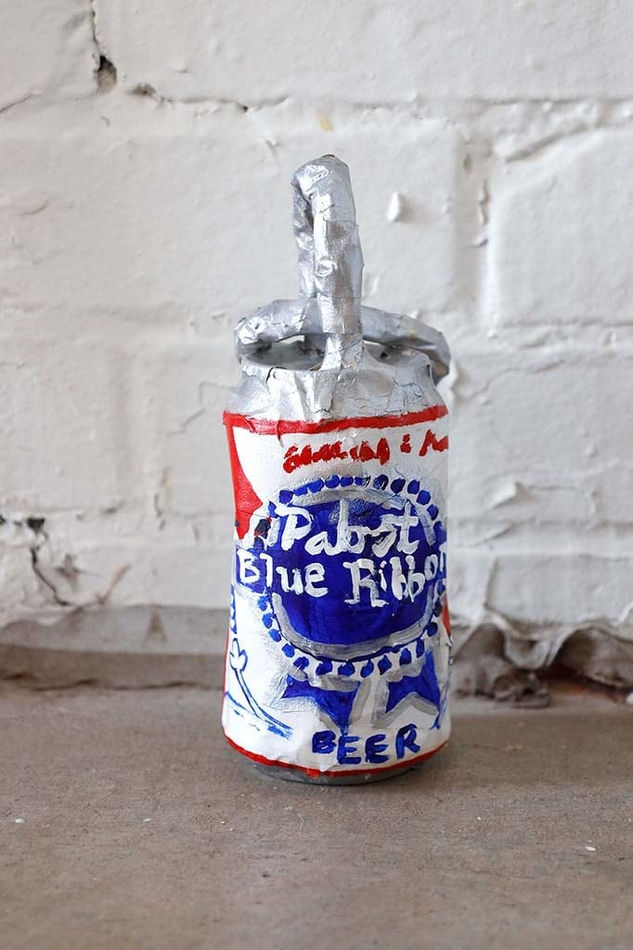 Soft sculpture of a Pabst Blue Ribbon can with two silver rings on the top