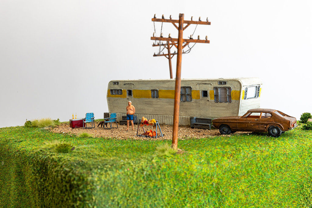 miniature diorama by Abigail Goldman of woman being roasted over an open flame in front of an RV