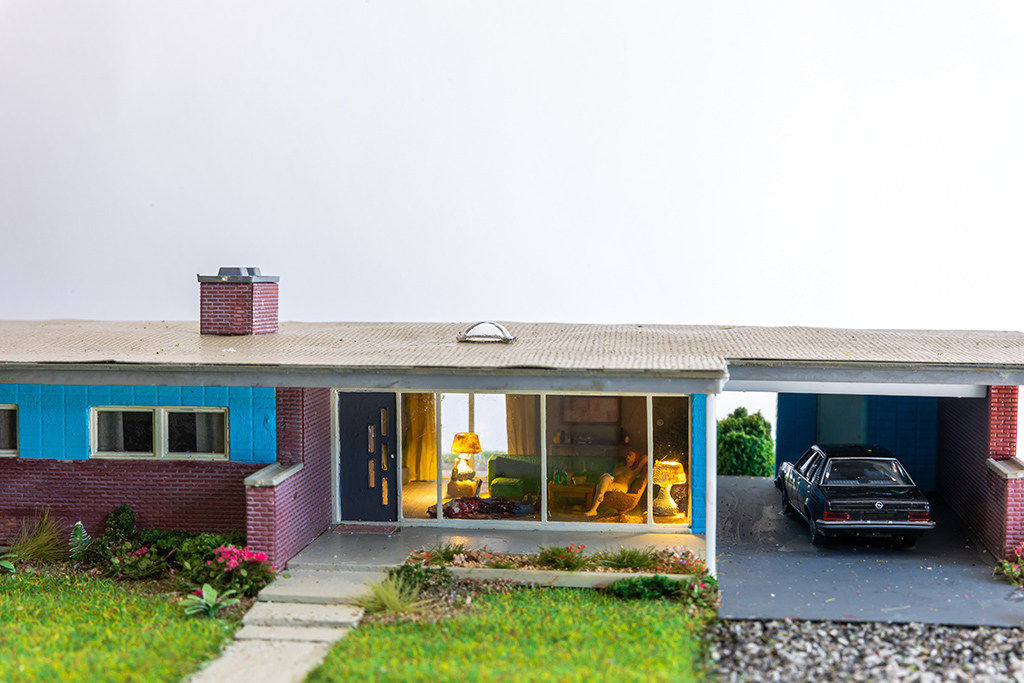 miniature diorama by Abigail Goldman of a naked woman sitting inside a house next to dead bodies
