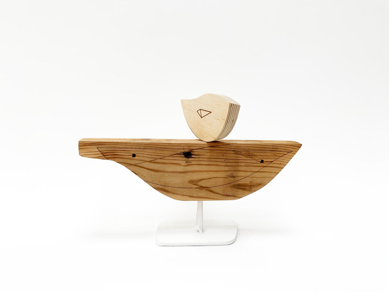 Wooden sculpture of a bird on a boat shaped object by Hyland Mather