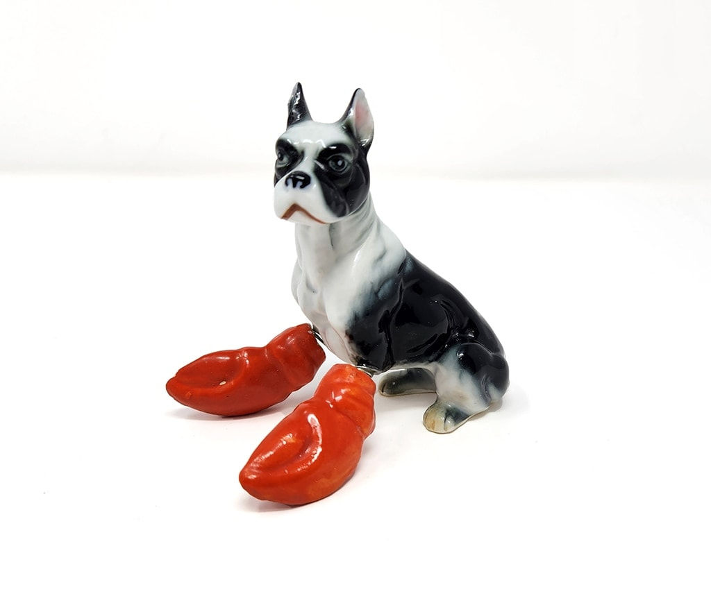 Debra Broz - ceramic and mixed media sculpture, black and white bulldog with red lobster claw replacing the front legs, dog in sitting position