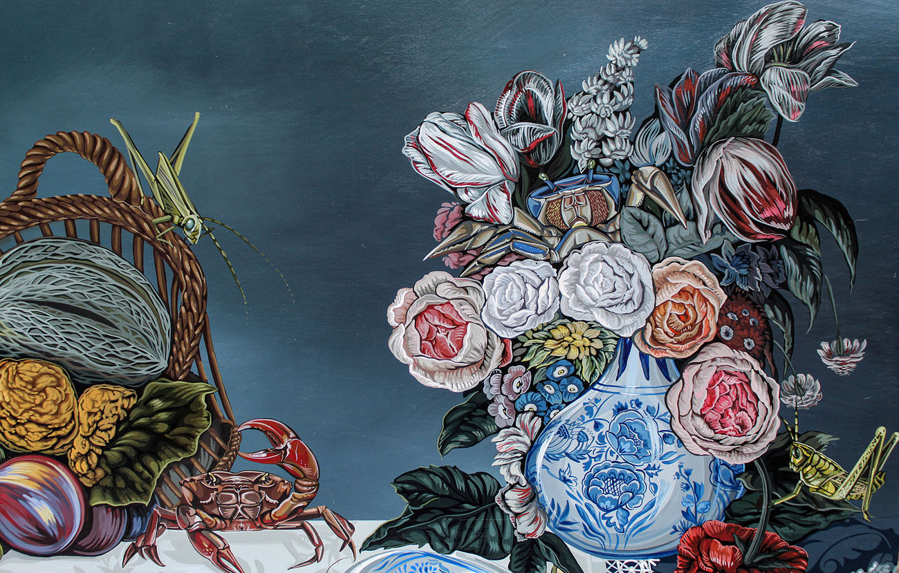 Tablescape painting of two black and white dogs on a table full of decadent food, including a basket of fruit with a grasshopper on it, a giant bouquet of flowers, a bowls of strawberries that has been know knocked over, a plate of giant shrimp, a bowl of whole fish and a white frosted cake that one of the dogs has walked into and gotten frosting all over the table.