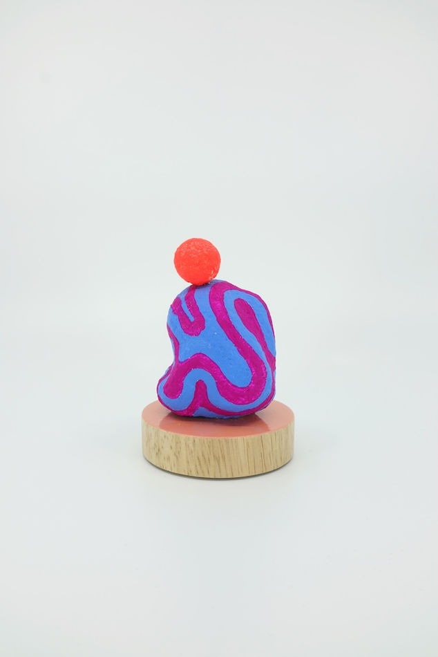 Magenta and blue sculpture with an orange sphere on top of it