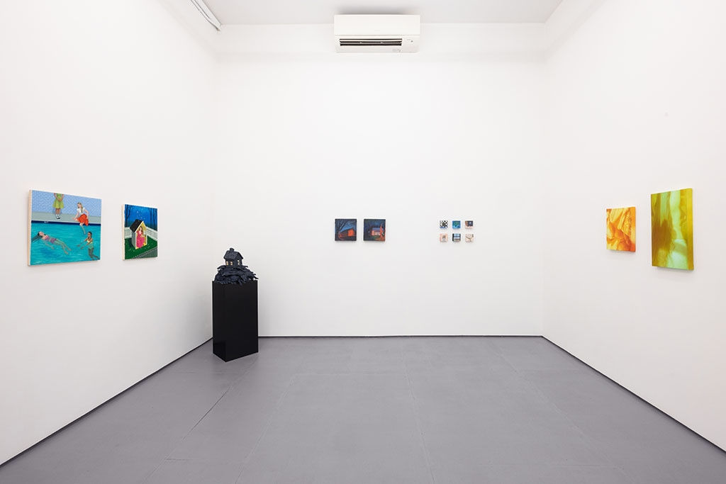 white gallery walls with paintings of various sizes and a black pedestal with a sculpture in the corner