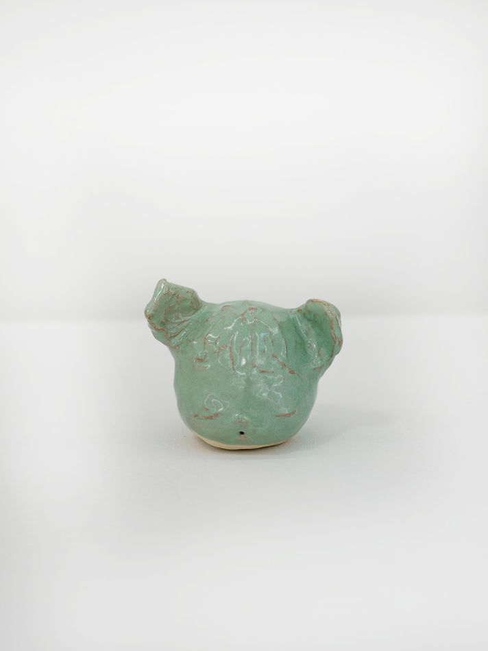 Ceramic sculpture of a the artists dog head in a mint green glaze