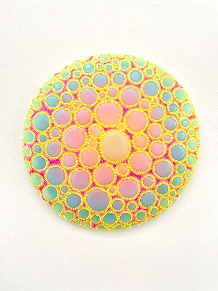 Circular sculpture by Dan Lam with multicolor circles and tiny bright yellow spikes.
