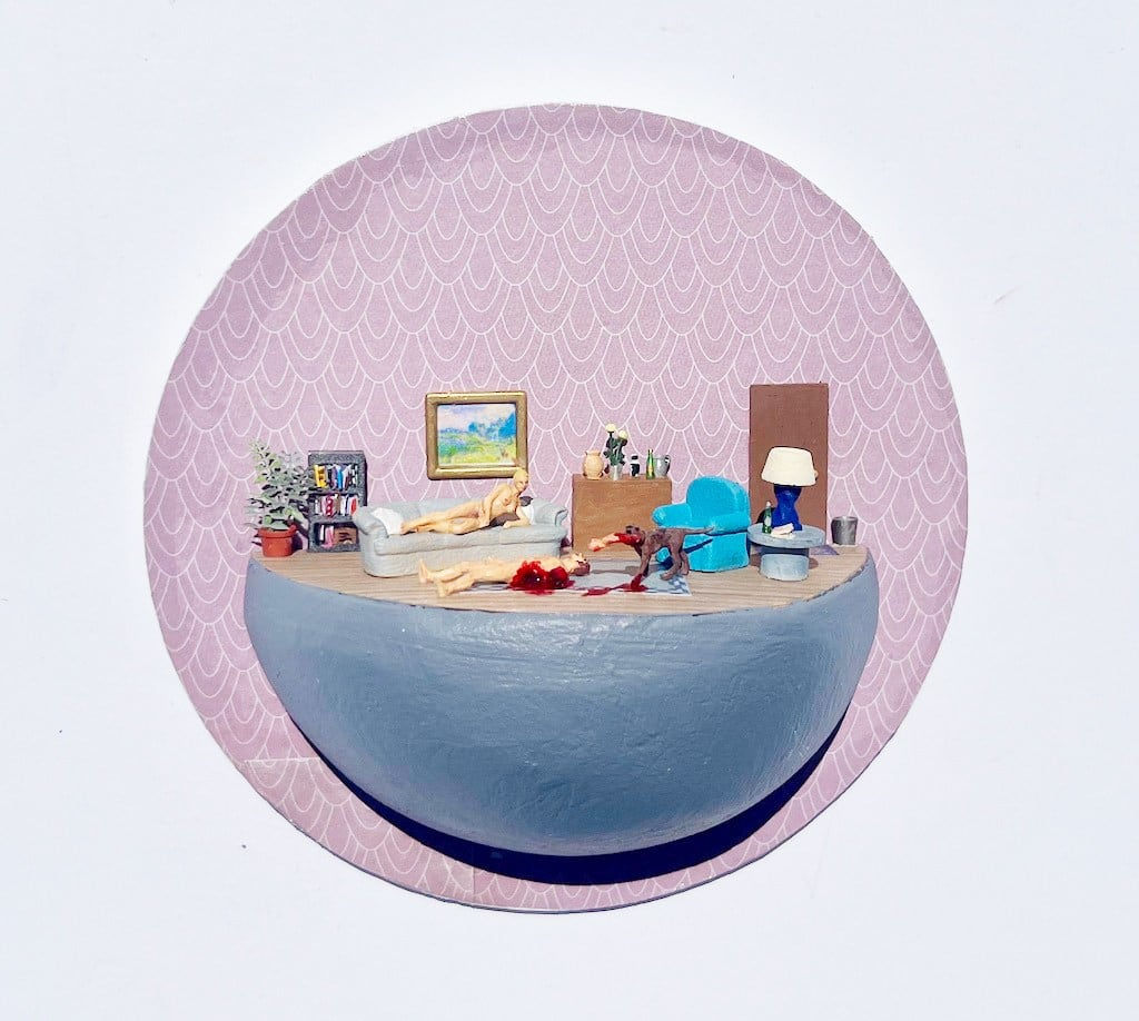 Miniature scene of a naked woman on a couch, on the ground below her is a man with his arm ripped off, a dog is standing above him with his arm in its mouth. The man is bleeding all over the rug below him.