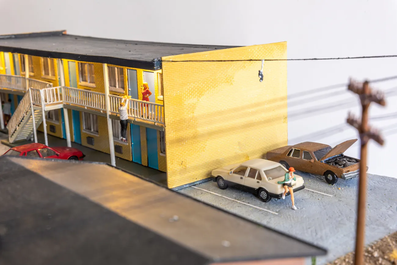 miniature diorama by Abigail Goldman of a woman bleeding on the ground in the parking lot of a motel