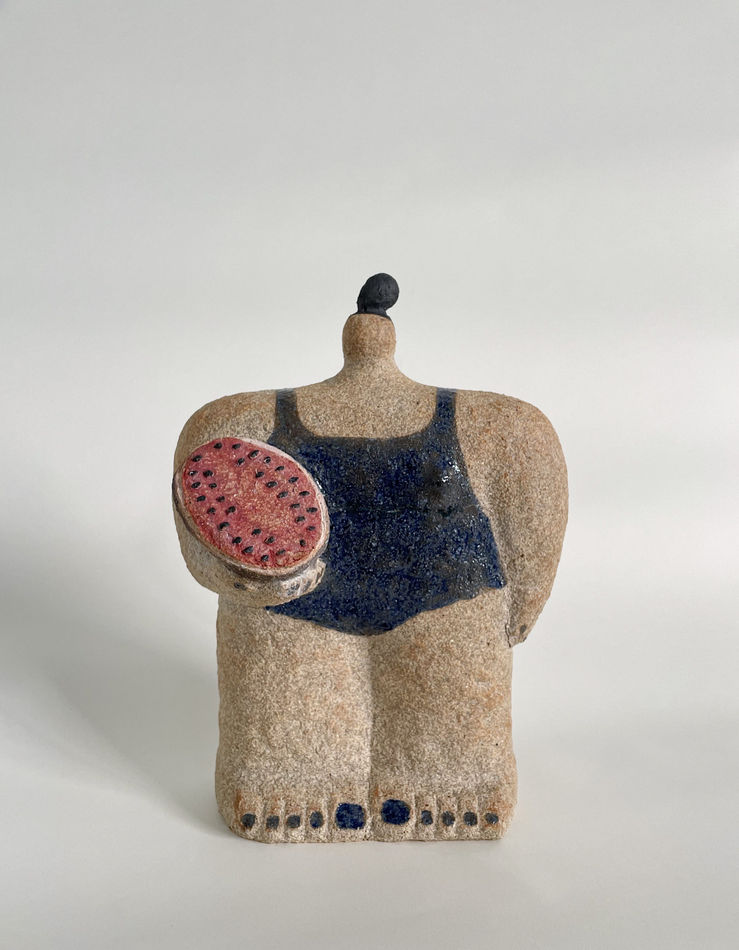 Ceramic sculpture of a figure wearing a navy bathing suit and holding a watermelon