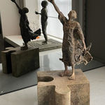 “Eureka” bronze sculpture by Lieven D’Haese, featuring a figure standing on a monumental puzzle piece and raising another fragment upward in a gesture of discovery.