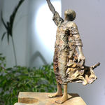 Sculpture en bronze “Eureka” de Lieven D’Haese, représentant une figure debout sur une pièce de puzzle monumentale, levant un fragment vers le ciel dans un geste de découverte.