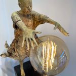 Visionary XL, sculpture lumineuse en bronze de Lieven d'Haese représentant un garçon ouvrant les bras pour allumer une ampoule, symbole d'imagination, de magie et de rêve. Sculpture d'art contemporain, design lumineux et design d'intérieur, exposée à la galerie Art Yi à Bruxelles.