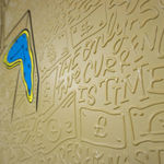 Detail photo of “El Tiempo”, painting by Cayla Birk artist from South Florida. Available at Carousel Fine Art Chicago. The artist’s technique blends traditional acrylic paints with unique materials, creating a distinct mixed media style. Birk's work is marked by intricate designs and recognizable gestures, combining contemporary culture, history, music, and literature. Her art challenges conventional thinking, offering new and unexpected experiences. Colors of this work : Blue, Yellow, Beige, Black