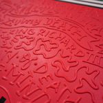 Detail photo of “El Tiburón”, painting by Cayla Birk artist from South Florida. Available at Carousel Fine Art Chicago. The artist’s technique blends traditional acrylic paints with unique materials, creating a distinct mixed media style. Birk's work is marked by intricate designs and recognizable gestures, combining contemporary culture, history, music, and literature. Her art challenges conventional thinking, offering new and unexpected experiences. Colors of this work : Red, Blue, Teal, Beige, White, Black