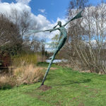 A monumental bronze sculpture of a winged female stands in front of trees at a Dorset sculpture park, Sculpture by the Lakes