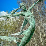 A monumental bronze sculpture of a winged female stands in front of trees at a Dorset sculpture park, Sculpture by the Lakes